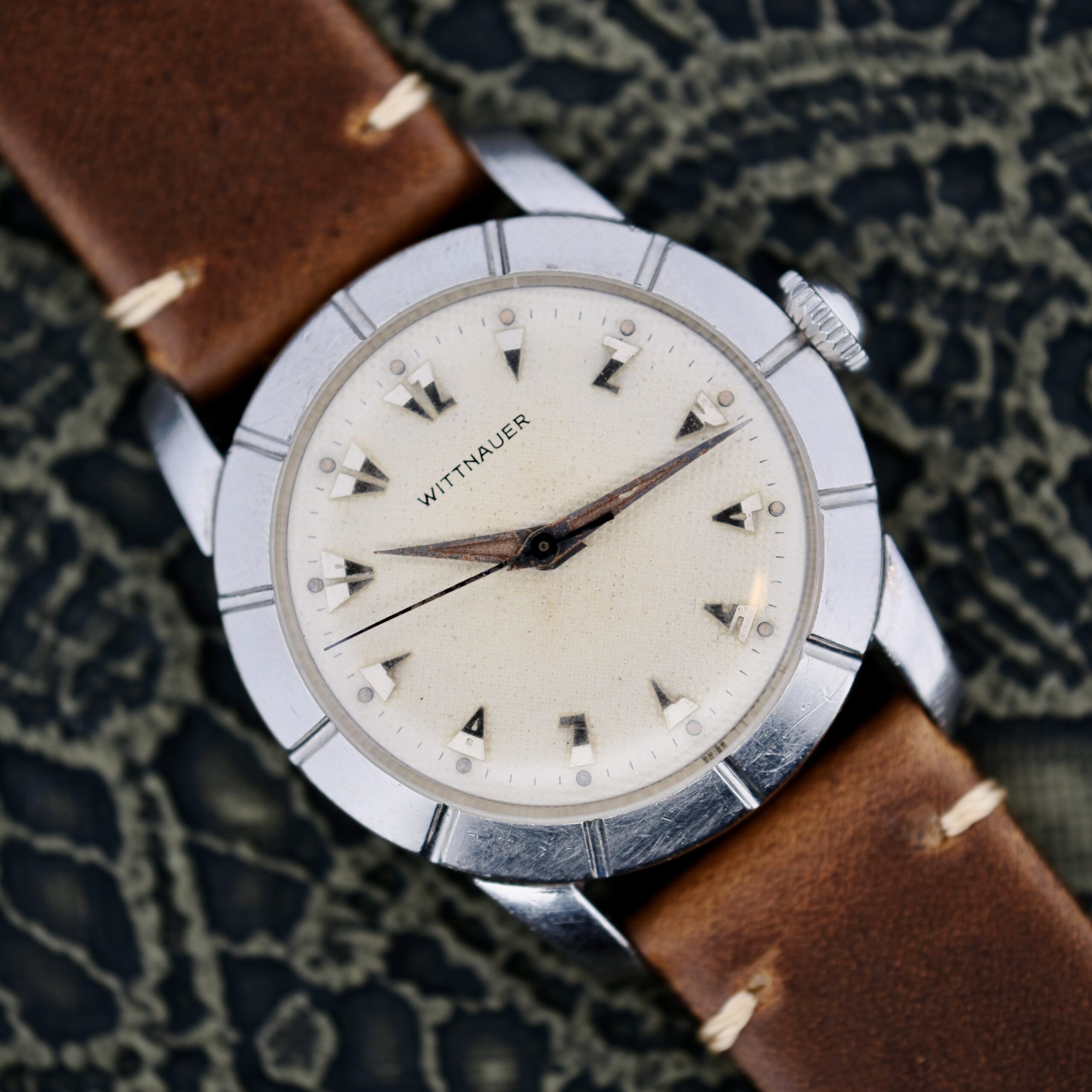 A Wittnauer 2065 Waffle Dial with Art Deco indices, brown leather strap, silver case, and off-white dial with silver triangular hour markers and black hands, displayed against a textured dark background.