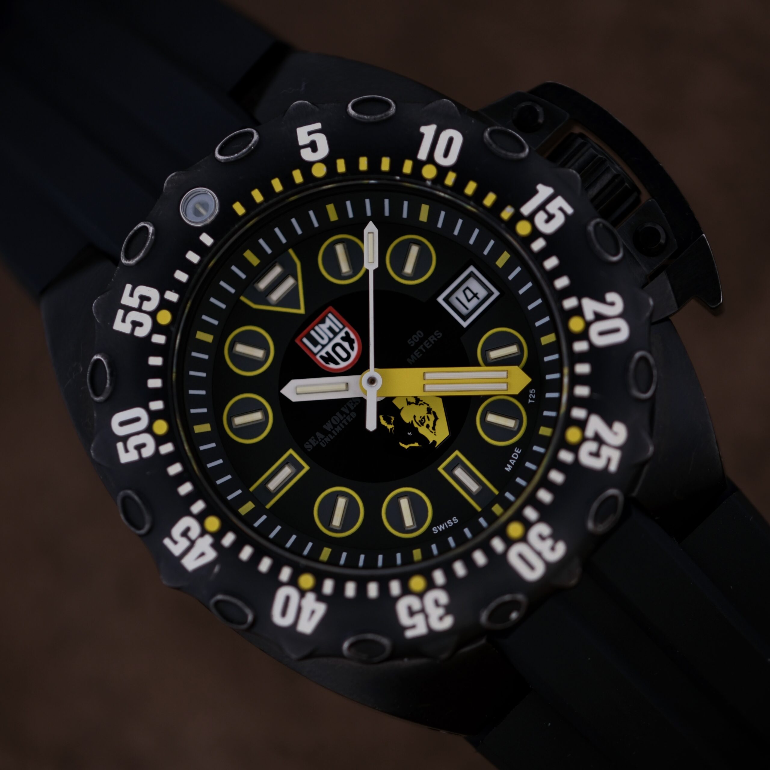 Close-up of the Luminox Scott Cassell Deep Dive Specia 1526 Automatic wristwatch, showcasing bold yellow numerals and markers with logos on the dial. The bezel displays white numbers at intervals against a dark background.
