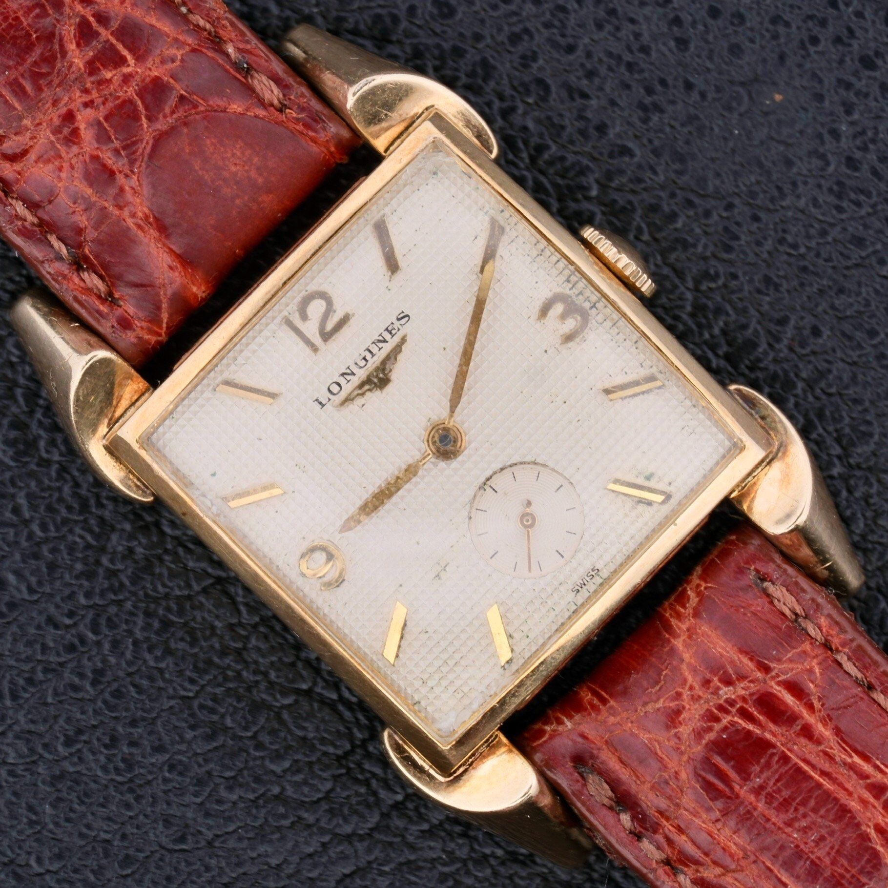 A vintage Longines Franklin Square Waffle Dial Cal 23Z watch with a gold casing, brown leather strap, minimalistic hour markers, and a small subdial at the base.