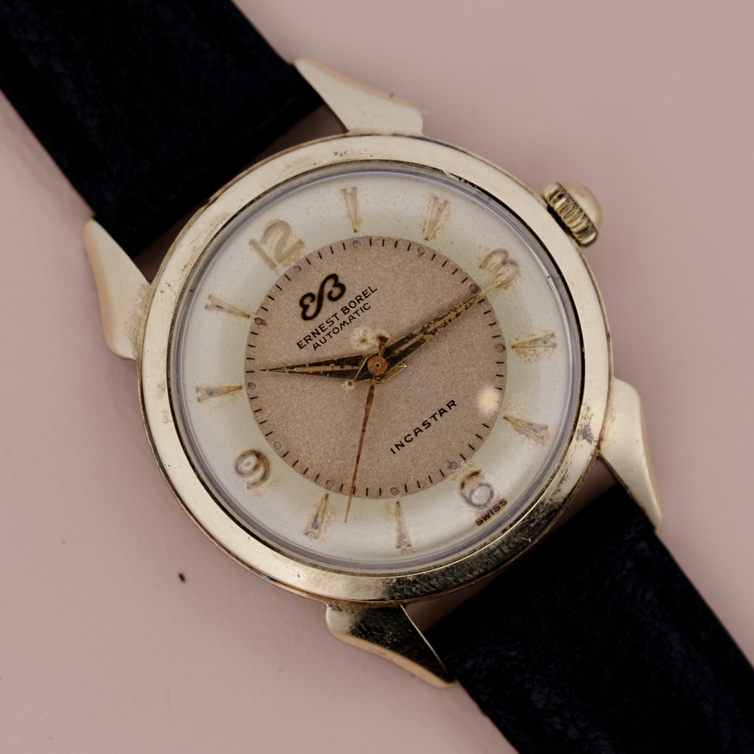 A close-up of the Ernest Borel Incastar 1560 Gold Capped wristwatch, featuring a gold case, black leather strap, Arabic numerals, and gold hour, minute, and second hands. The dial displays Ernest Borel, Automatic, and Incastar.